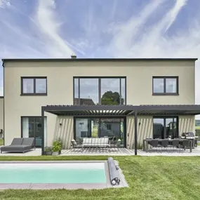 Modernes Einfamilienhaus mit Flachdach, Terrasse, Gartenmöbeln und Pool im Grünen.